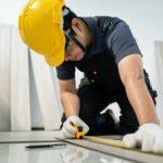 Asian Craftsman worker man use tape measure parquet on corridor to install laminate board on floor