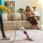 Female janitor with vacuum cleaner in room