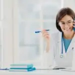 Glad professional doctor concentrated in modern laptop