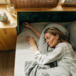 Top view of a sleeping woman. Clock and pills on the nightstand next to the bed.