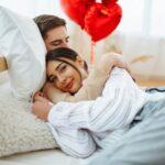 Young couple at home celebrating Valentine's Day. Exchange of gifts. Surprise and love concept.