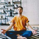 Young man sitting in easy seat yoga pose in living room