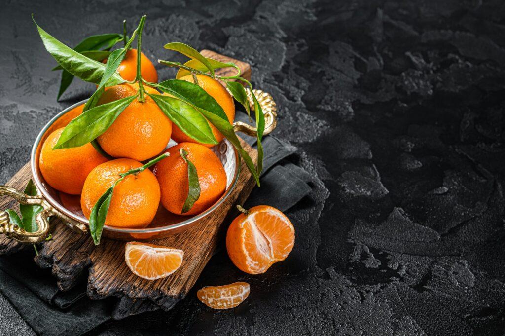 Clementines Tangerines with green leaves. Black background. Top view. Copy space