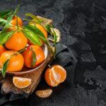 Clementines Tangerines with green leaves. Black background. Top view. Copy space