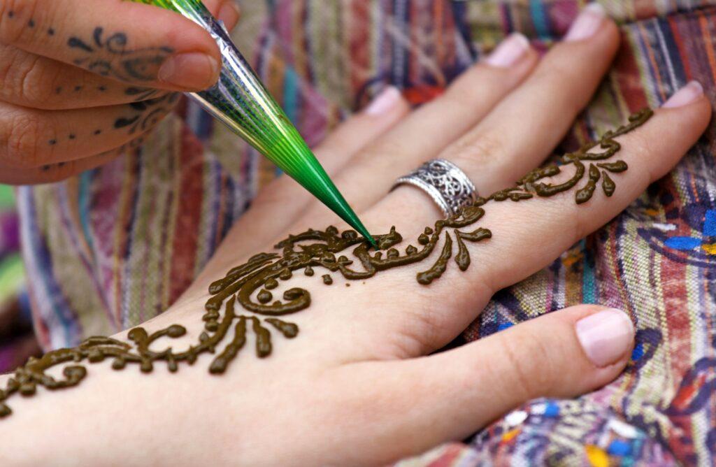 Human hand being decorated with henna tattoo