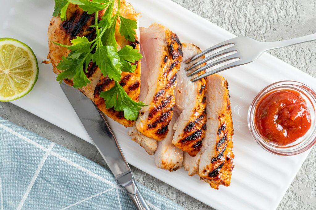 top view of slices of sliced grilled chicken fillet breast on a serving white rectangular plate