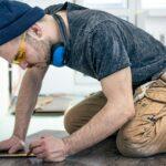 A male worker puts laminate flooring on the floor.