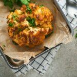 Baked cauliflower. Oven or whole baked cauliflower spices and herbs server on wooden rustic board on