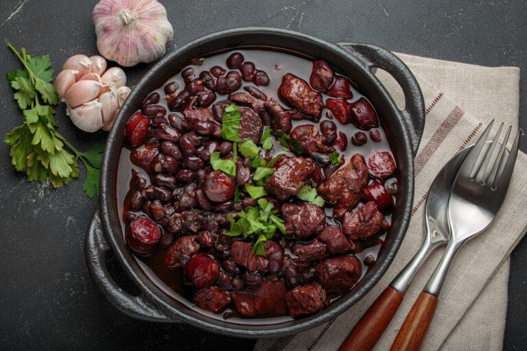 Brazilian feijoada with black beans, sausage and meat in a pot, top view