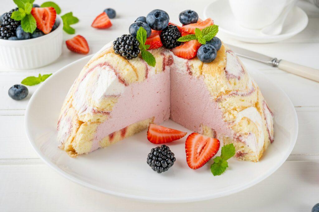 Charlotte Royale Cake with strawberry cream inside and decorated berries. Delicious summer cake.