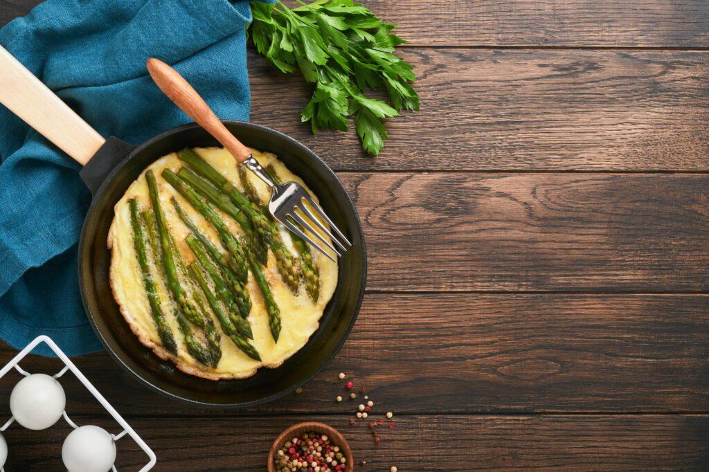 Omelet with asparagus. Frittata or scrambled with asparagus in frying pan with parsley and pepper on
