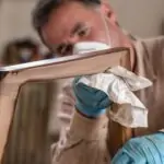 Process of applying oil-wax to wooden chair in carpentry workshop