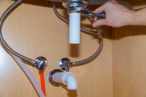 Plumber standing in front of washbasin writing of plumber repairing drain