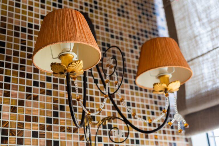 Two-lamp sconce with two fabric orange lampshades. Classic wall lamp in restaurant or hotel