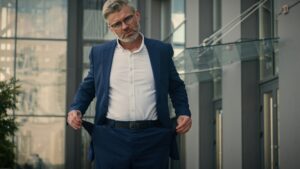 Caucasian mature sad senior business man show turn empty pants pockets bankrupt no money poverty