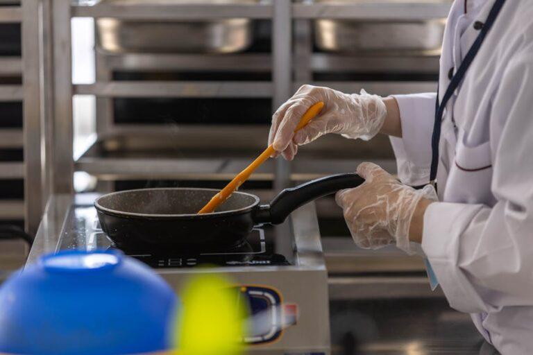 Réussir un risotto : les astuces essentielles des chefs italiens Chef in professional kitchen cooking with frying pan using stovetop.