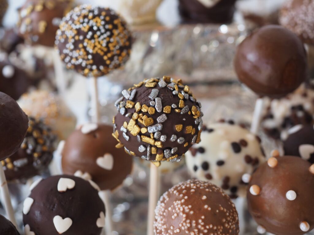 Gros plan sur des cake pops variés avec chocolat et garnitures décoratives, parfaits pour les tables de dessert.