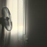 white wall fan turned on near white window blinds