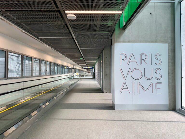 Transfert depuis et vers Roissy CDG : comment se déplacer sans stress Modern airport walkway with "paris vous aime" art