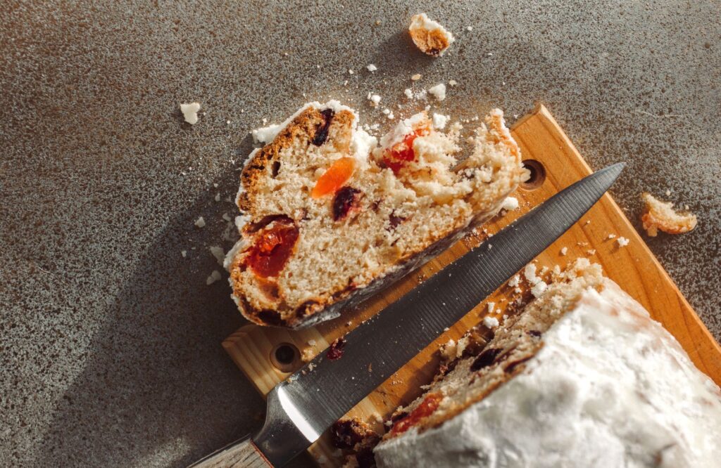 Gros plan rustique d'une tranche de gâteau aux fruits avec un couteau sur une planche à découper, mettant en avant des textures délicieuses.