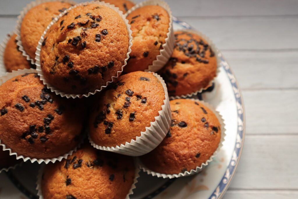 Délicieux muffins aux pépites de chocolat sur une assiette en céramique, parfaits pour un dessert ou une collation.