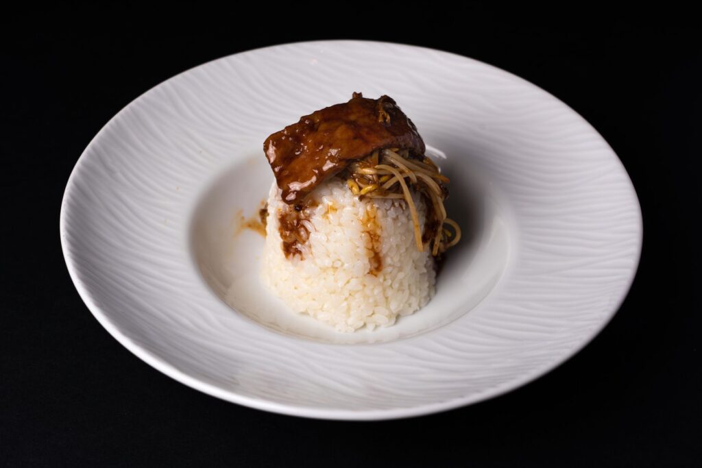 Plat élégant de boeuf et de champignons sur du riz, présenté sur une assiette en céramique.