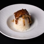 Plat élégant de boeuf et de champignons sur du riz, présenté sur une assiette en céramique.