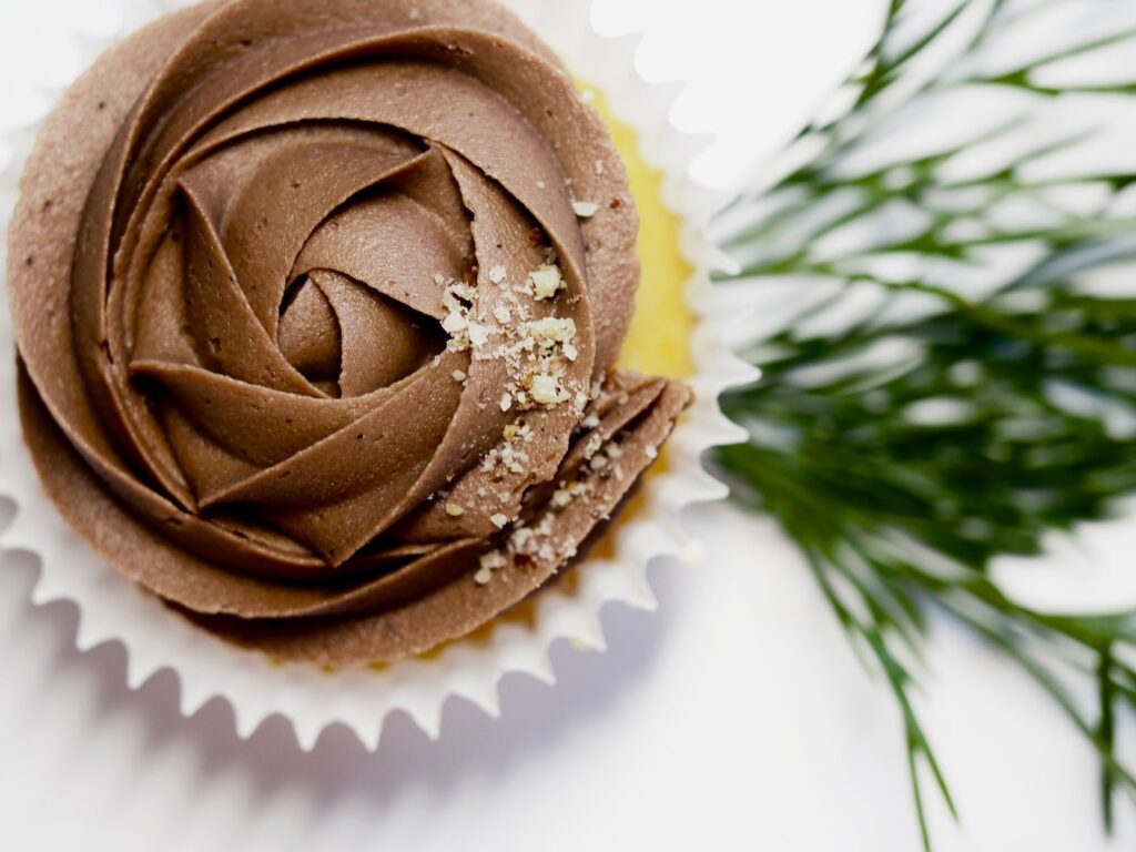 Gros plan sur un cupcake au chocolat avec un glaçage complexe et une touche de verdure, parfait pour une douceur.