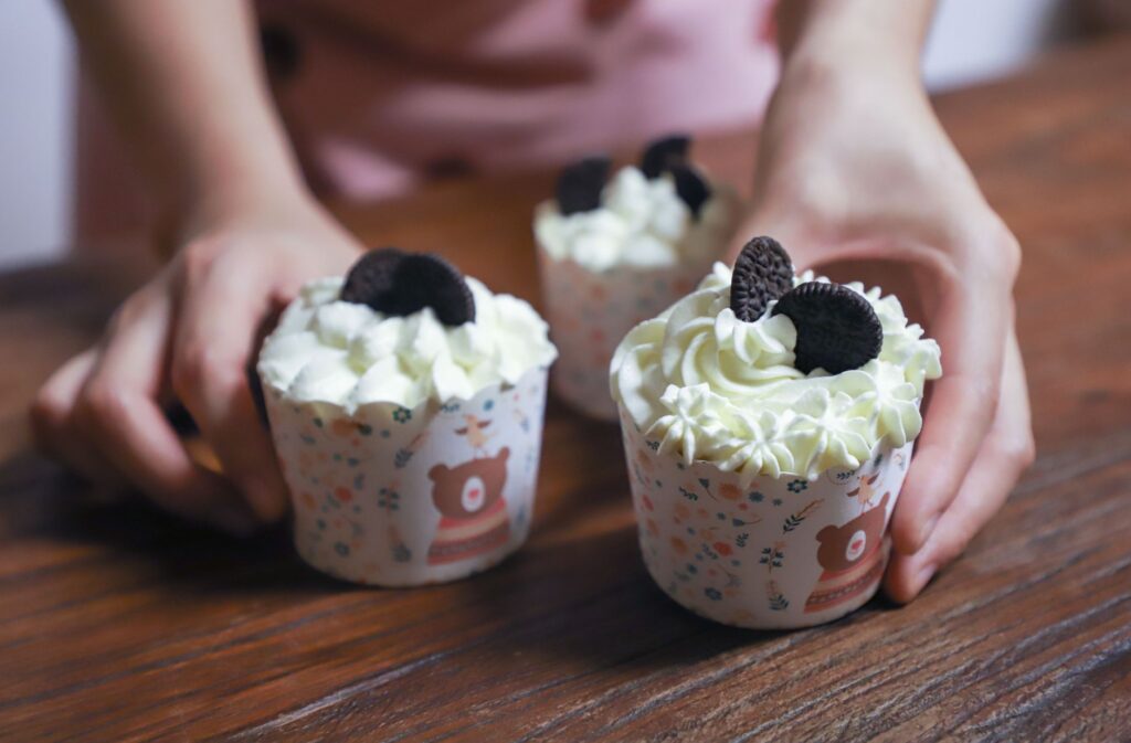 Des cupcakes fraîchement préparés avec un glaçage crémeux et des cookies Oreo sur une table en bois.