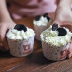 Des cupcakes fraîchement préparés avec un glaçage crémeux et des cookies Oreo sur une table en bois.
