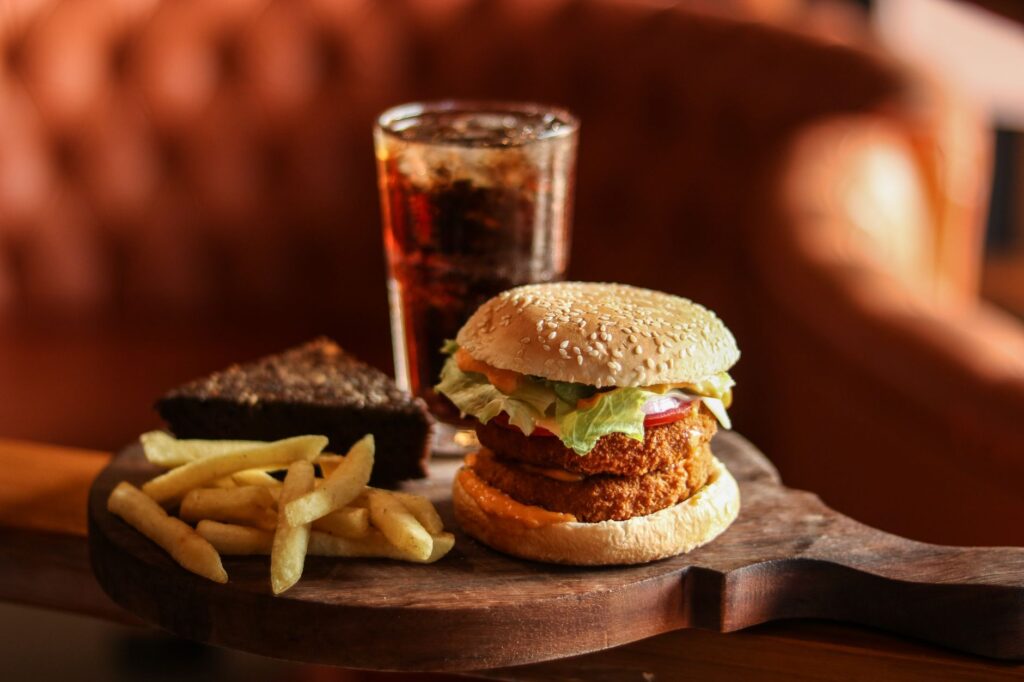 Burger savoureux, frites, brownie et cola sur une planche en bois pour un repas satisfaisant.