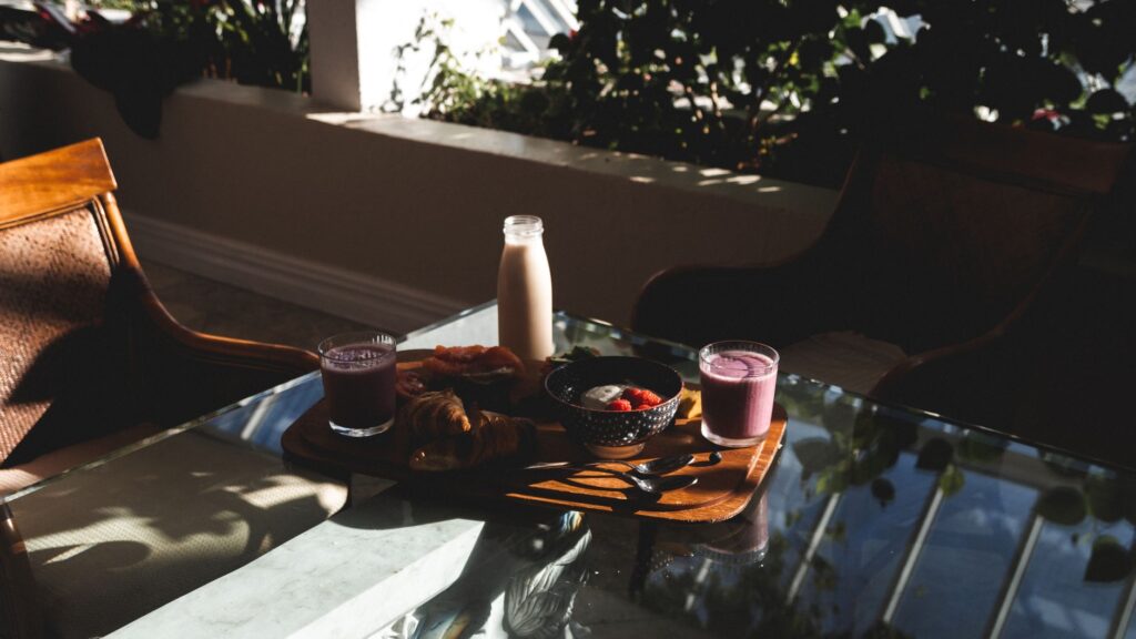 Petit déjeuner chaleureux avec des croissants, des fruits et des smoothies sur une table de balcon. Idéal pour des thèmes de style de vie.