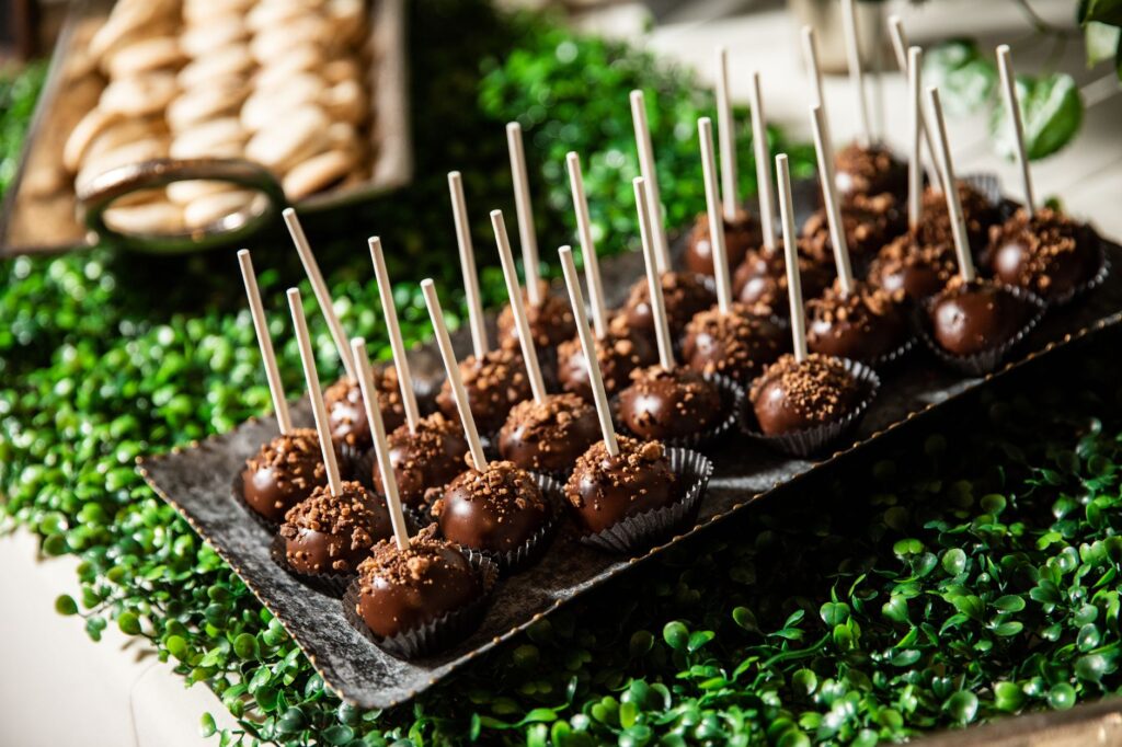 Délicieuses boules de gâteau au chocolat élégamment présentées sur un plateau entourées de verdure, parfaites pour une douceur.