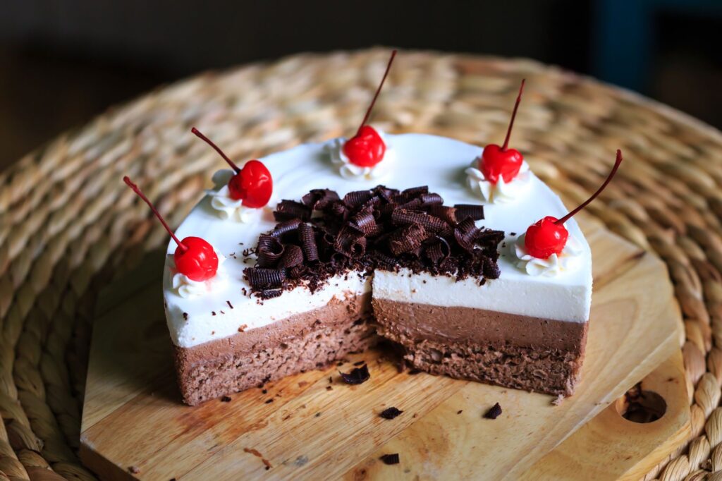 Délicieux gâteau mousse au chocolat, garni de crème, de cerises et de copeaux de chocolat.