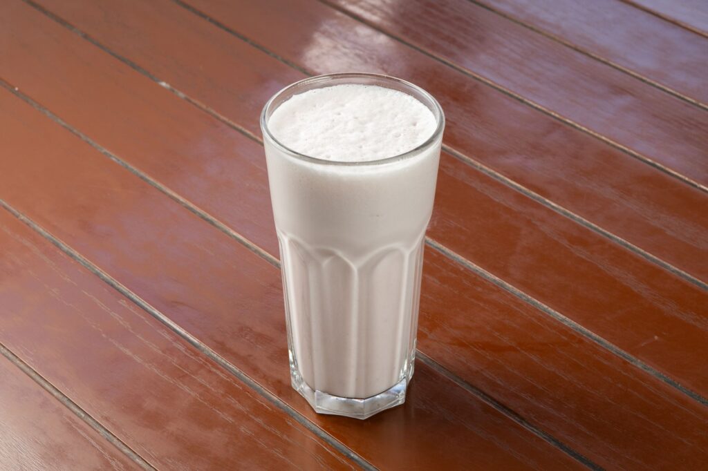 Un milkshake vanille crémeux dans un verre sur une table en bois, parfait pour se désaltérer.