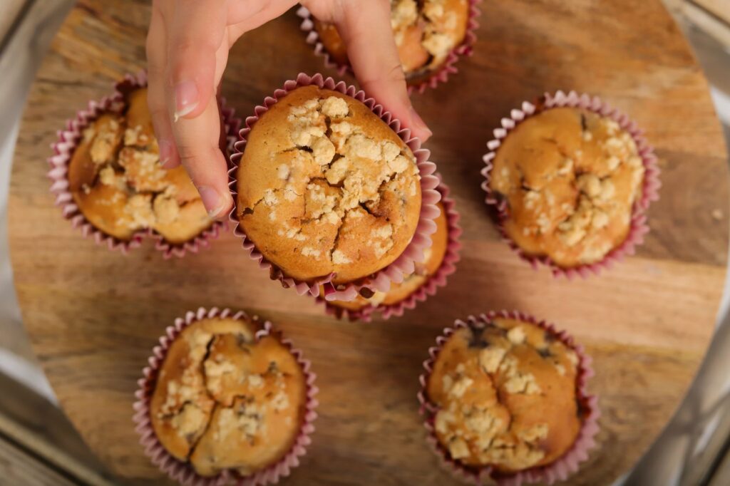 Choisir à la main un muffin fraîchement cuit parmi un groupe sur un plateau en bois.