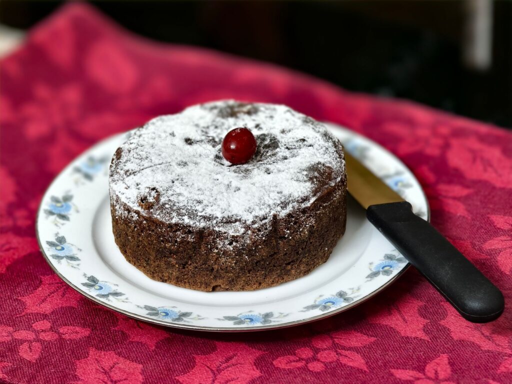 Gâteau au chocolat décadent garni d'une cerise, servi sur une assiette fleurie - parfait pour les festivités.