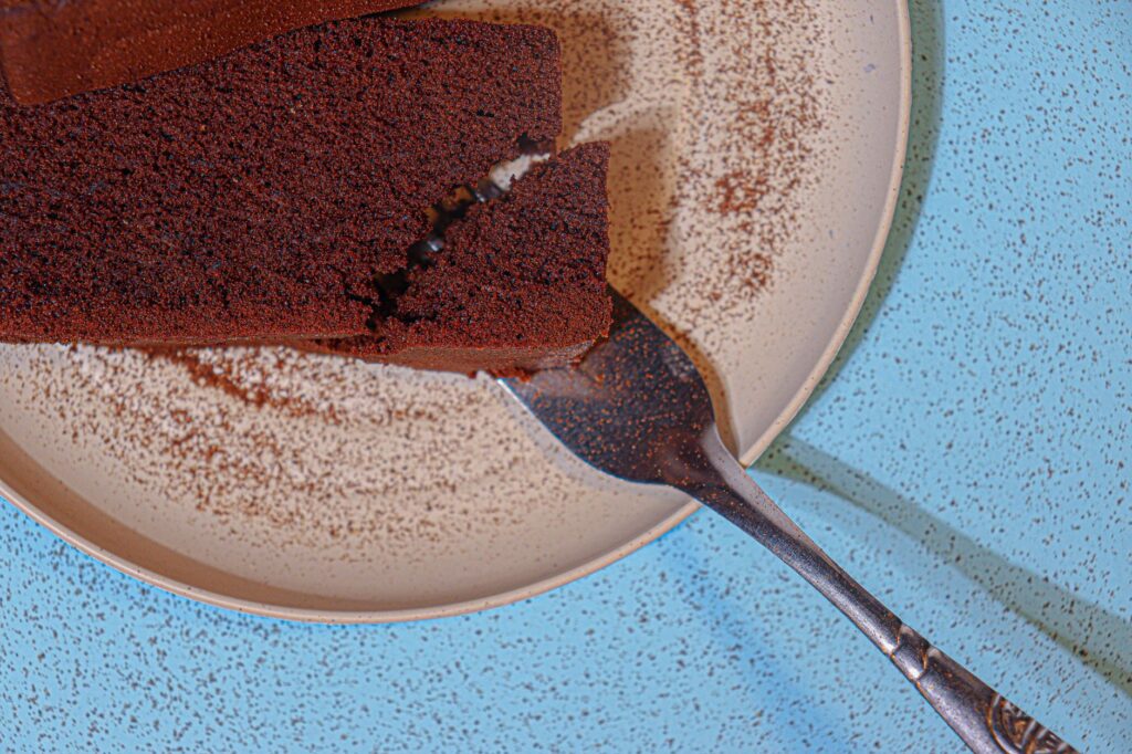 Une délicieuse tranche de gâteau au chocolat avec une fourchette sur une assiette mouchetée. Parfait pour les amateurs de desserts.