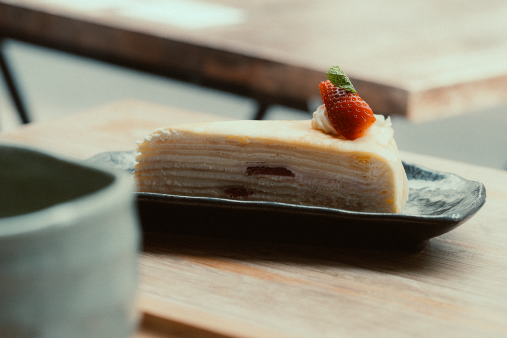 Une délicieuse tranche de mille-crêpes garnie de fraises fraîches, parfaite pour le dessert.