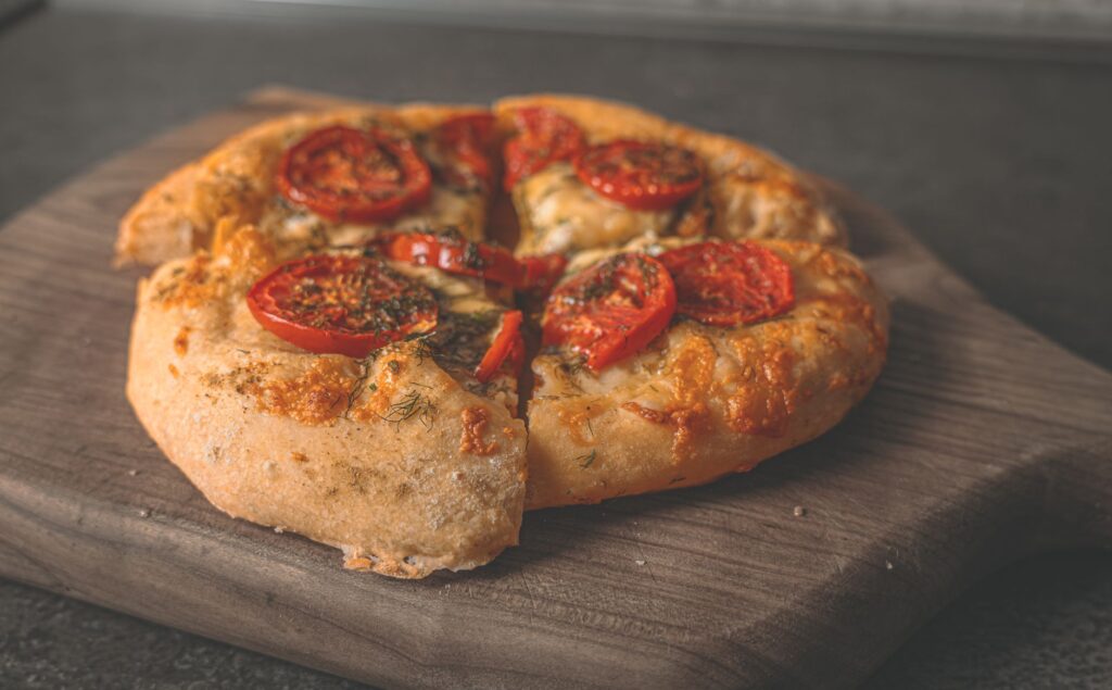 Savoureuse pizza maison garnie de tomates fraîches et de fromage sur une planche en bois.