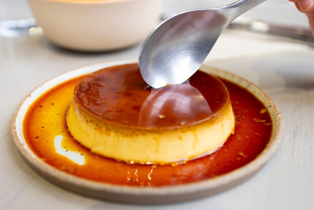Gros plan d'un dessert au flan au caramel servi dans un café chaleureux à Tokyo.