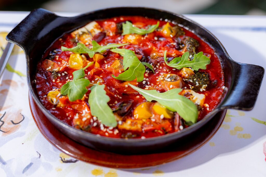 Ragoût de légumes fraîchement préparé garni de roquette, servi dans une poêle noire.