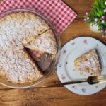 Délicieux gâteau aux amandes fait maison avec du sucre en poudre et une tranche servie sur une table rustique.