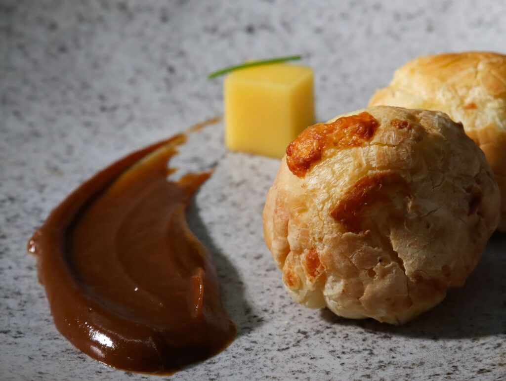 Pâtisseries salées au fromage garnies de sauce et de cube de fromage sur une surface en marbre, idéales pour les thèmes gastronomiques.