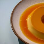 Délicieux flan crémeux au caramel servi sur une assiette en céramique à la texture onctueuse dans une douce lumière douce.
