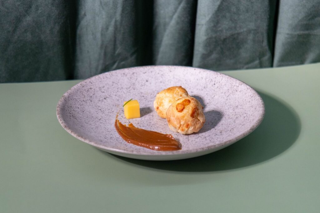 Une pâtisserie gourmande sur une assiette élégante, accompagnée de caramel et d'un cube de fromage. Parfait pour la photographie culinaire.