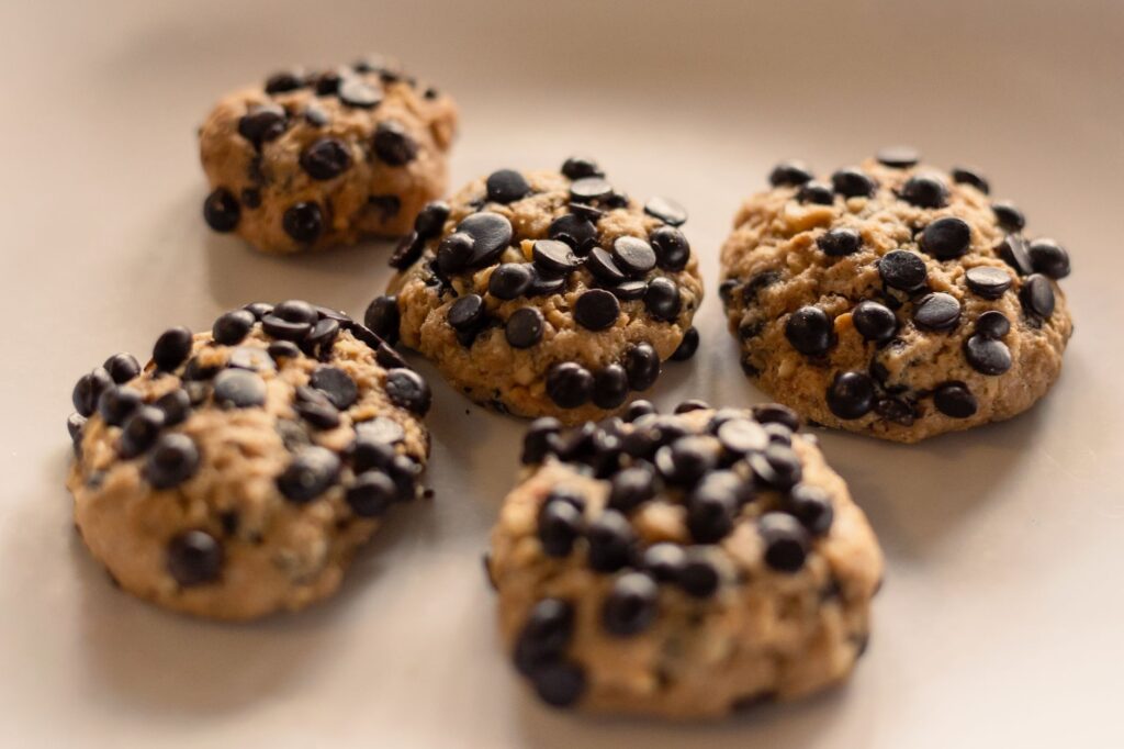Gros plan sur des biscuits aux pépites de chocolat faits maison sur fond beige, mettant en valeur leur texture croustillante.