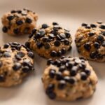 Gros plan sur des biscuits aux pépites de chocolat faits maison sur fond beige, mettant en valeur leur texture croustillante.