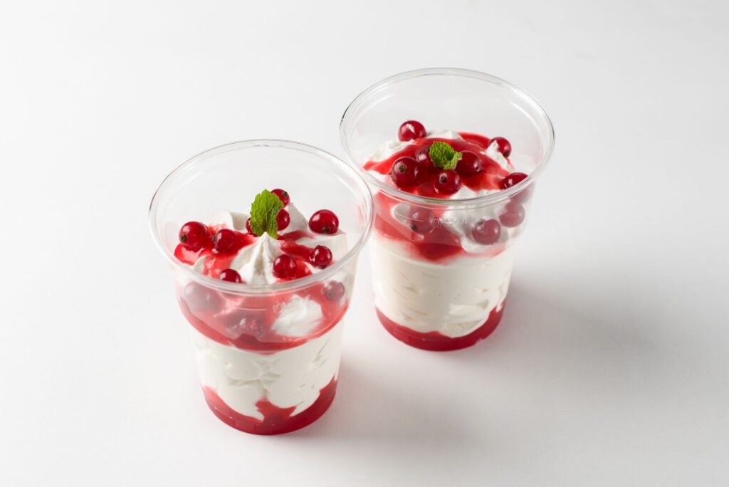 Deux délicieux parfaits aux fruits rouges, à la crème et à la menthe, servis dans des coupes transparentes.