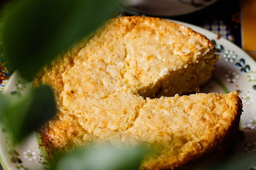 Gros plan sur un gâteau elote fait maison auquel il manque une part, présenté sur une assiette décorative.